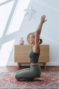 Elderly woman in sports clothing performing a yoga stretch indoors.
