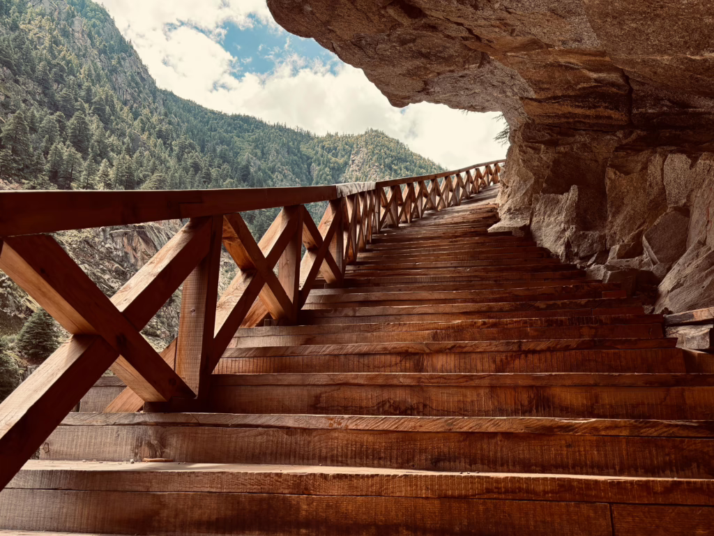 Scenic view of wooden stairs leading through a mountain passage in Bhatwari, showcasing nature's beauty.