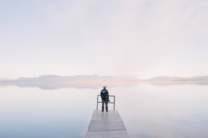A solitary traveler stands on a dock enjoying the serene water view