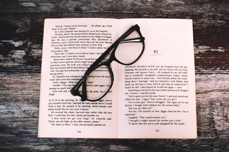 An open book with reading glasses placed on a rustic wooden table, inviting to read.